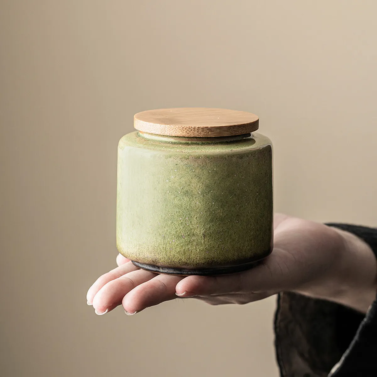 Boîte à thé verte à couvercle en bois tenue dans la paume d’une main