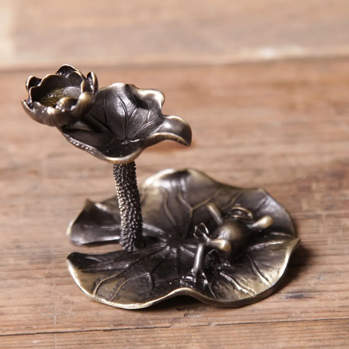 Petit brûle-encens lotus finition laiton posé sur une table en bois