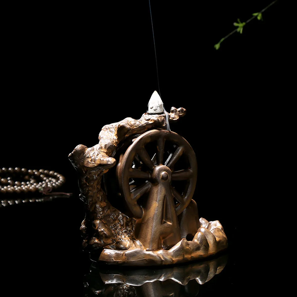 Brûle-encens moulin à eau en céramique avec un cône allumé, sur fond sombre