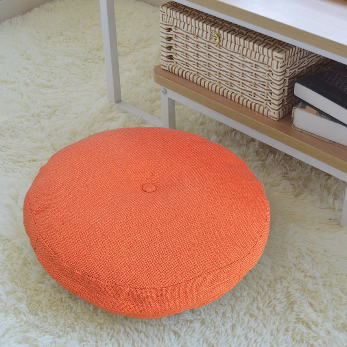 Coussin de sol rond orange posé sur un tapis moelleux, devant une étagère
