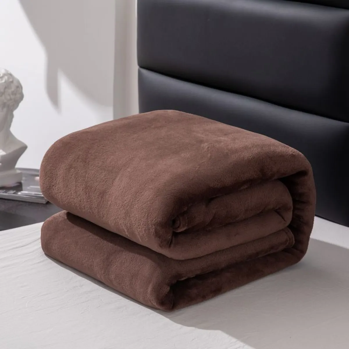 Couverture polaire marron pliée sur un lit