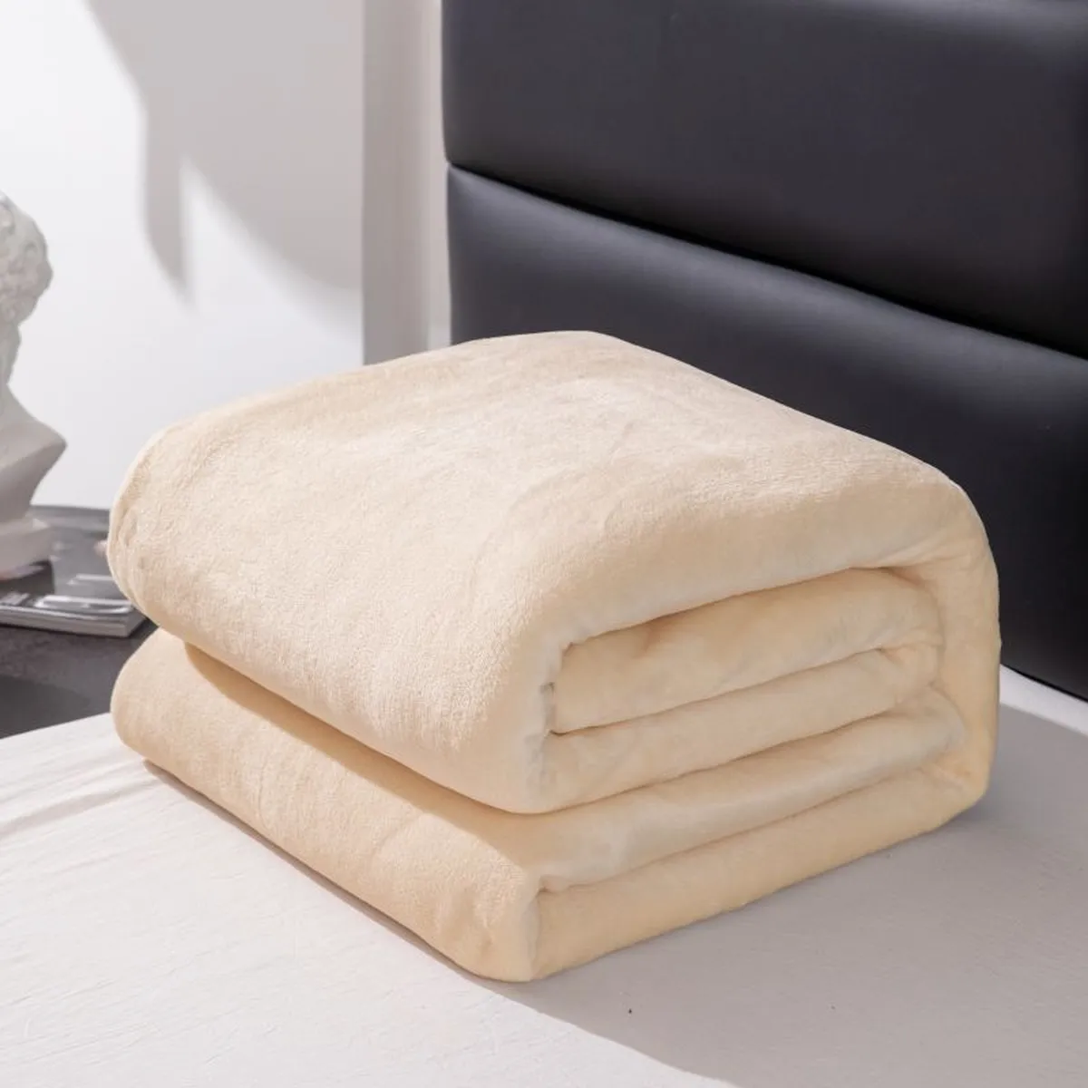 Couverture polaire beige pliée sur un lit