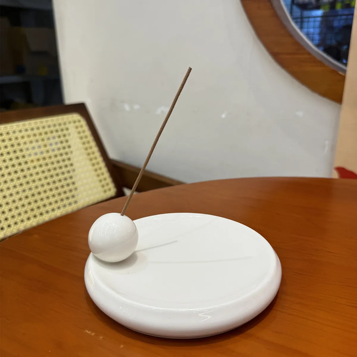 Porte-encens en céramique blanche à bille, un bâton planté, sur une table ronde
