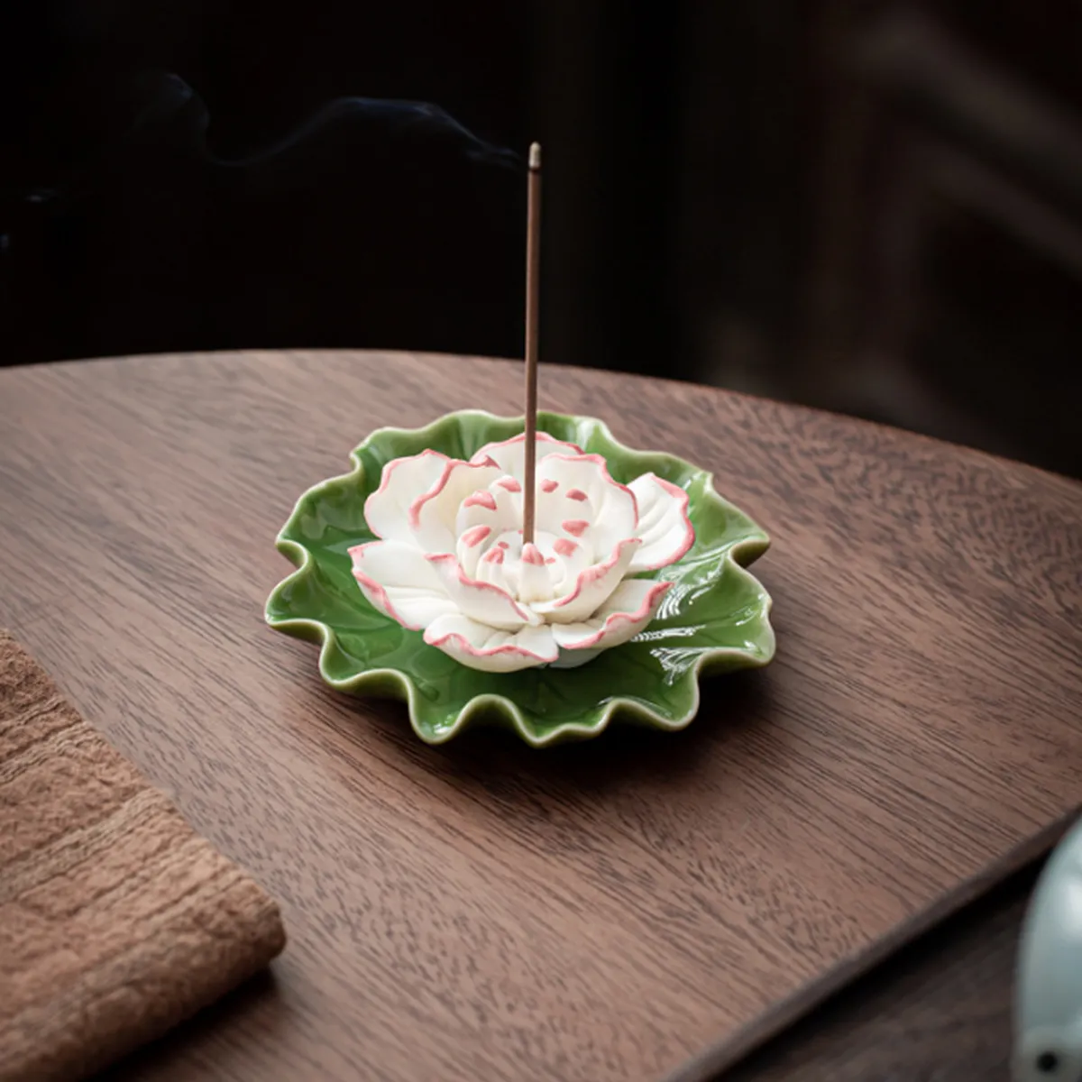 Porte-encens lotus blanc sur feuille verte, la fumée s’élève