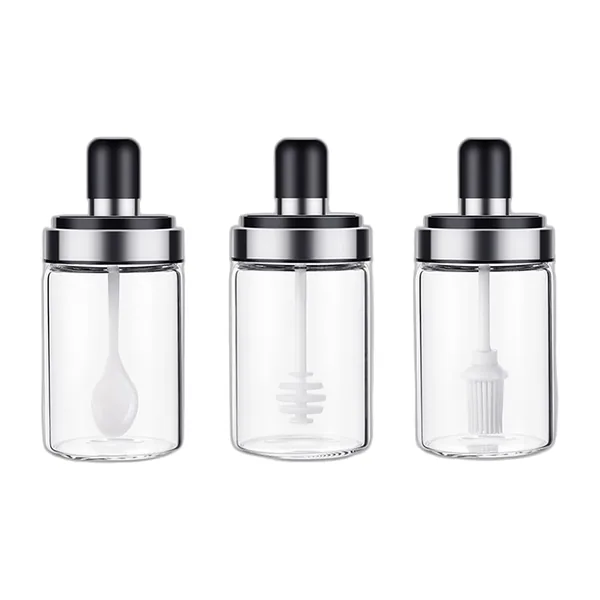 Trois pots en verre à couvercle noir : cuillère, cuillère à miel et pinceau