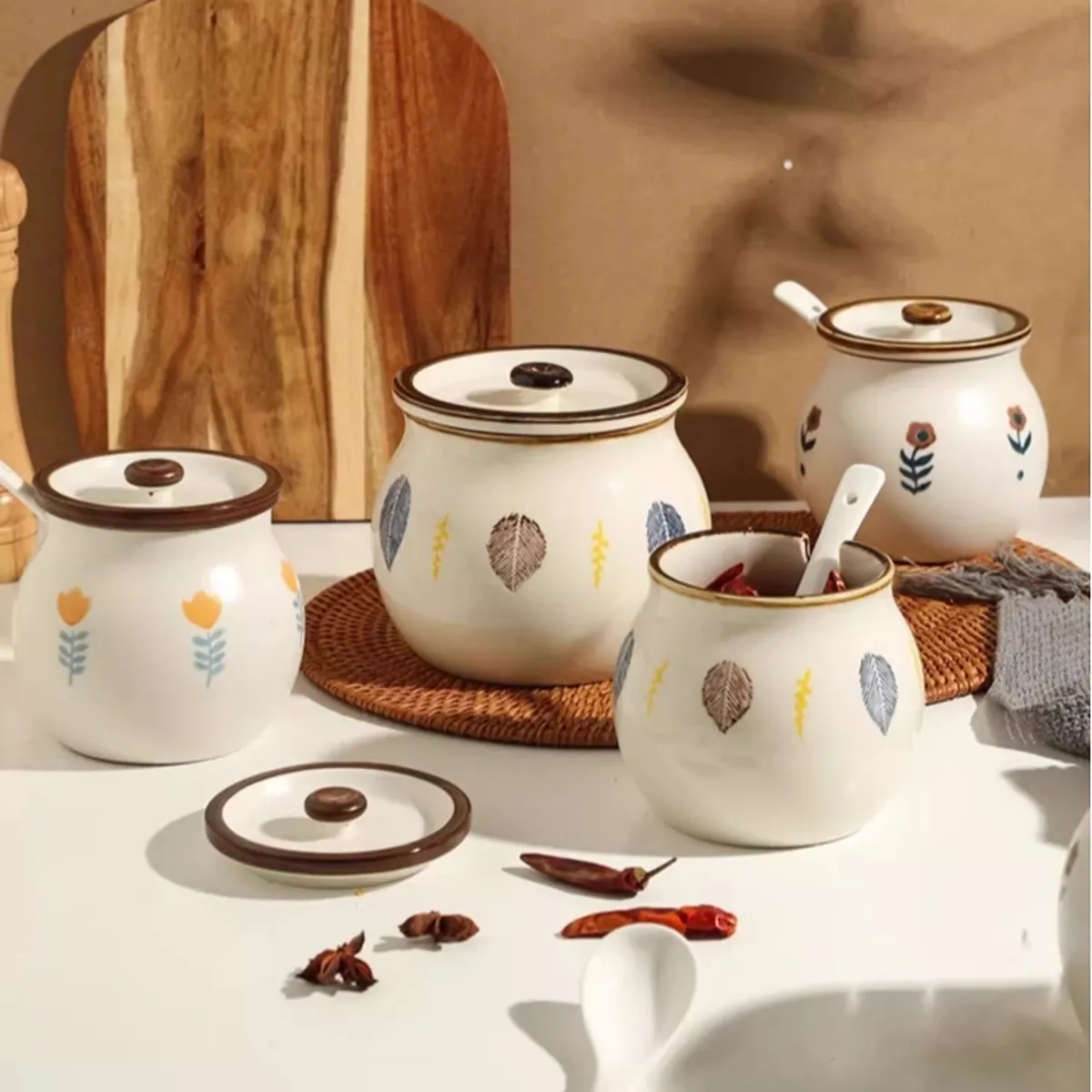 Pots en céramique peints de feuilles sur une table de cuisine, avec cuillères