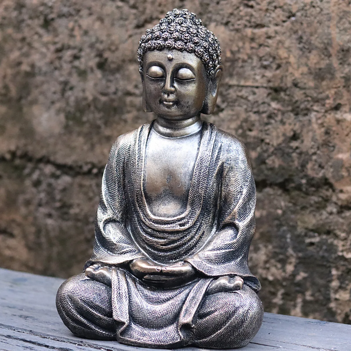 Statuette de bouddha patinée bronze sur un muret en pierre