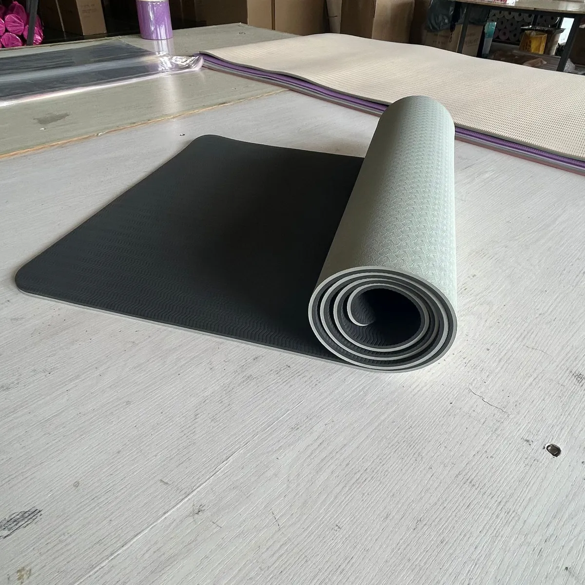 Tapis de yoga bicolore gris et noir à moitié déroulé sur une table