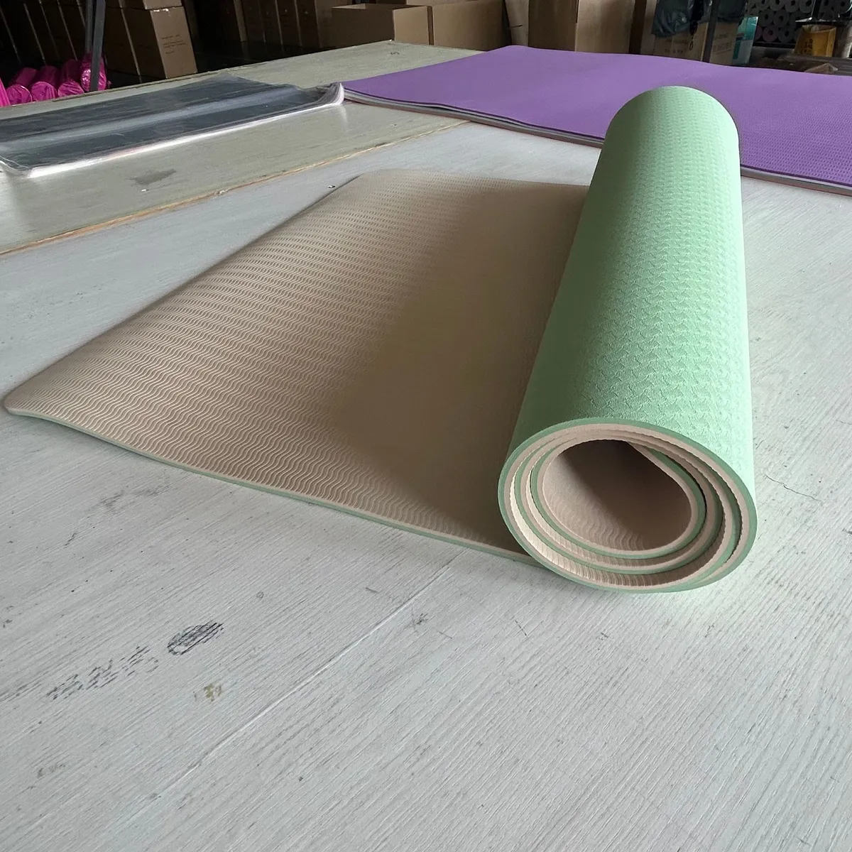 Tapis de yoga bicolore vert d’eau et taupe à moitié déroulé