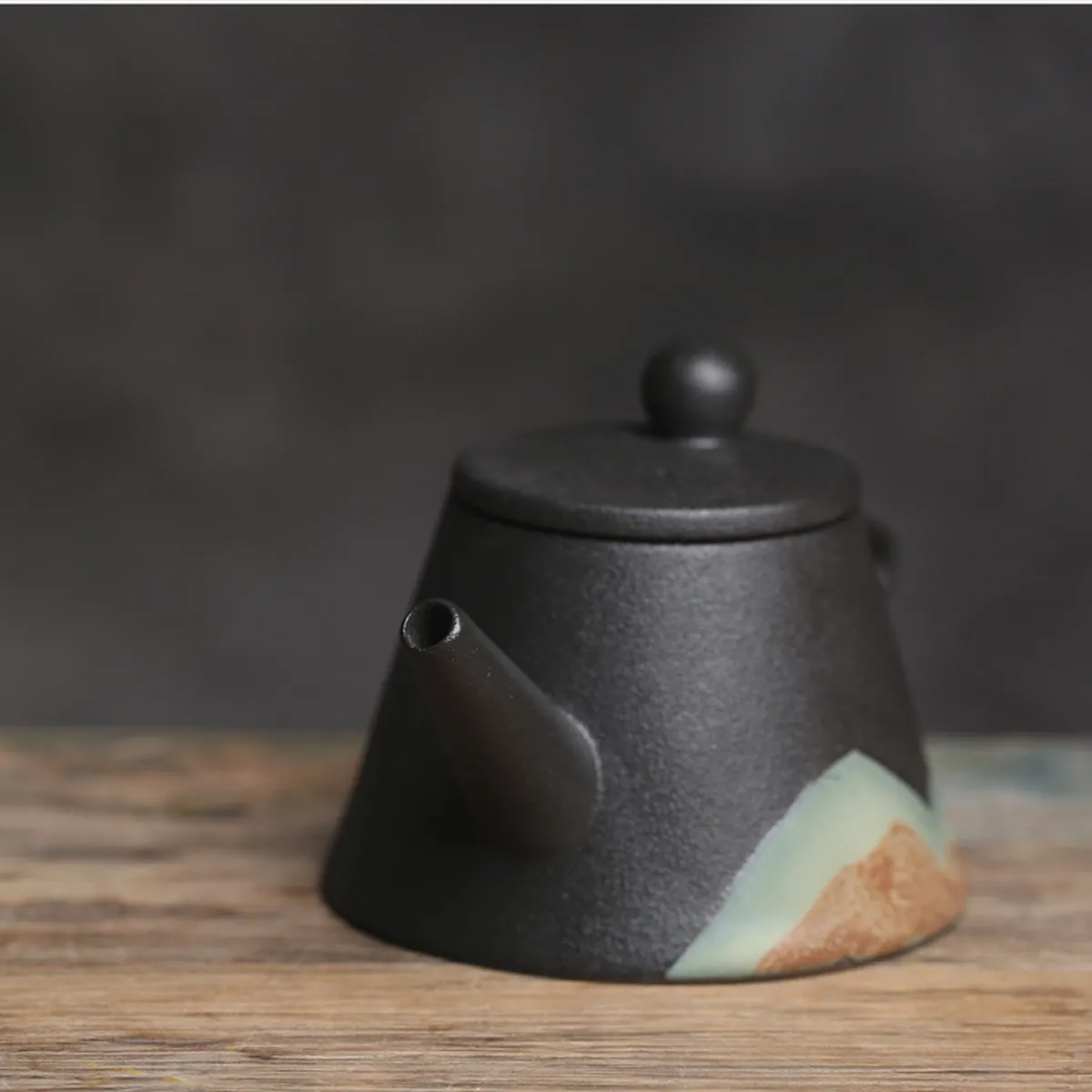 Théière en céramique mate au décor de montagne sur une table en bois